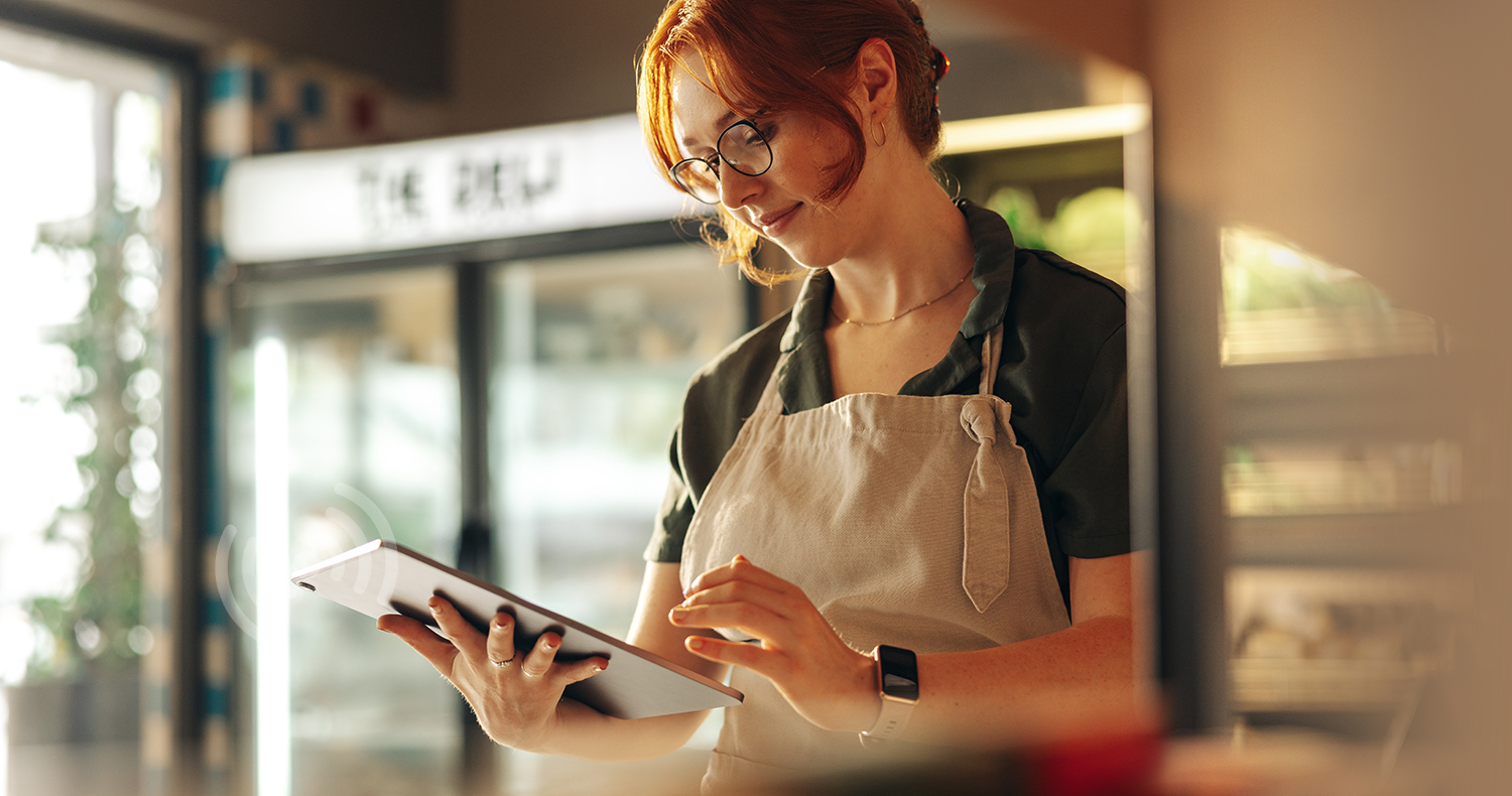 Cheerful shop owner using a digital tablet while standing in her grocery store. Successful female entrepreneur running her small business using wireless technology.