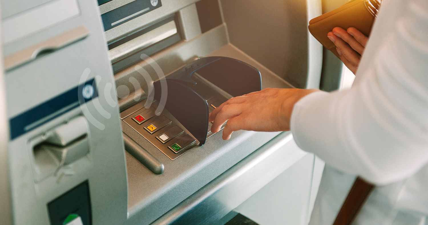 Woman using ATM holding wallet an pressing the PIN security number on the keyboard automatic teller machine