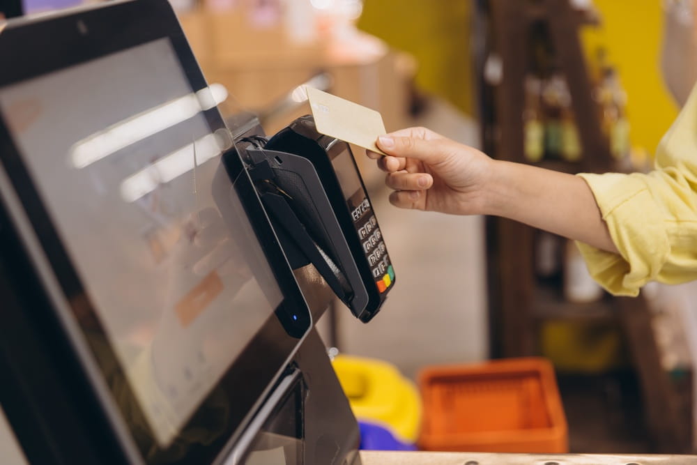 woman paying with touchless card at self-service checkout machine